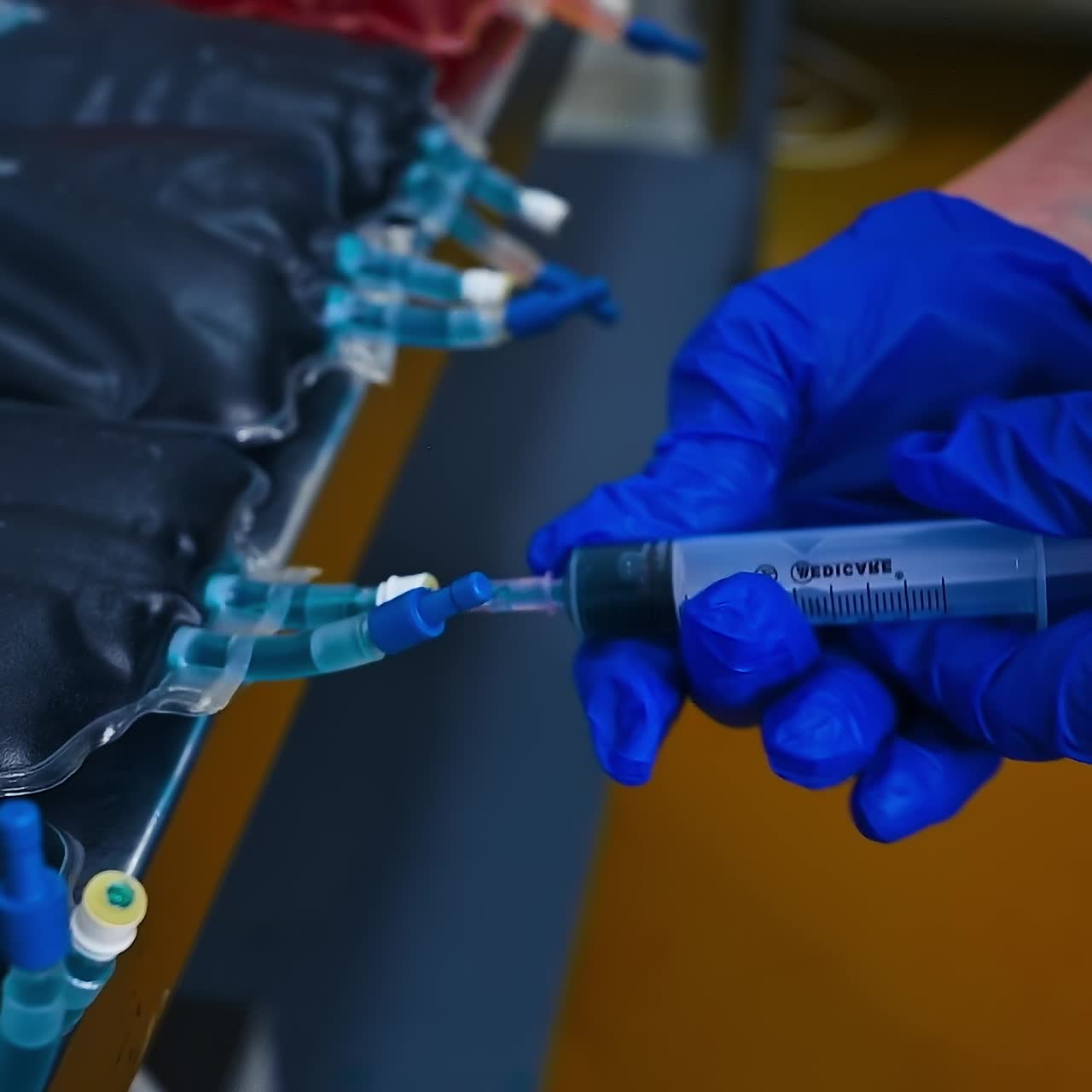 Worker fills syringe with vaccine for chicks. Hands in gloves of veterinarian dialing medicine from packs with vaccine. Close-up
