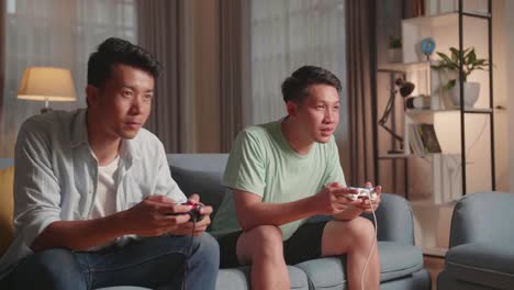 asian friends with joystick playing video games at home
