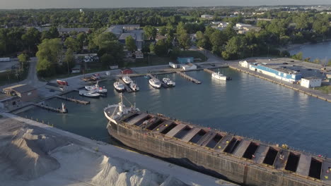 a huge industrial ship and yachts docked at the port in kingsville, ontario, canada on a sunny day - aerial shot