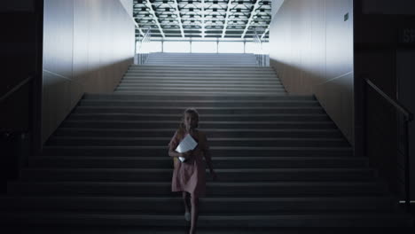 little girl going down school stairs enter empty hall. schoolgirl holding books.