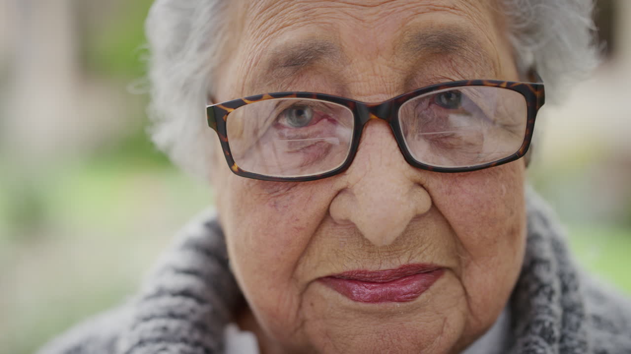 ritratto ravvicinato di una vecchia donna in pensione che si sente stanca e assonnata guardando la telecamera sullo sfondo del giardino