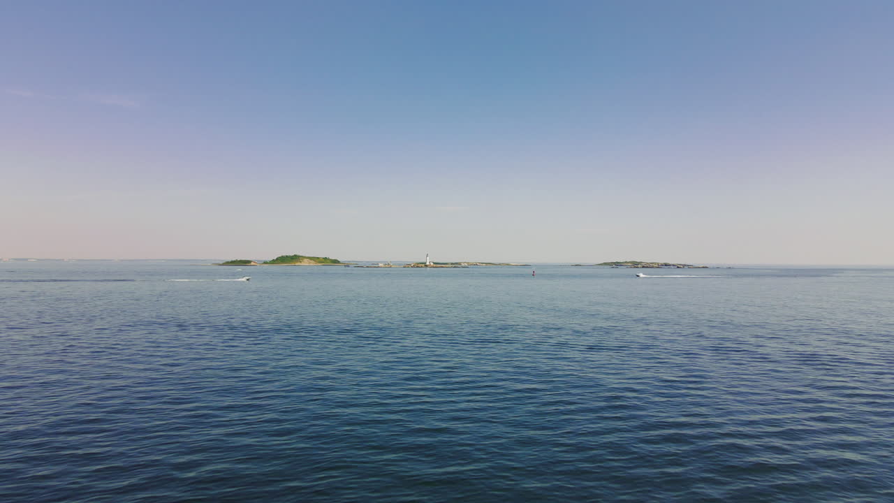 등대가 있는 섬 앞을 가로지르는 2대의 쾌속정 항공 영상