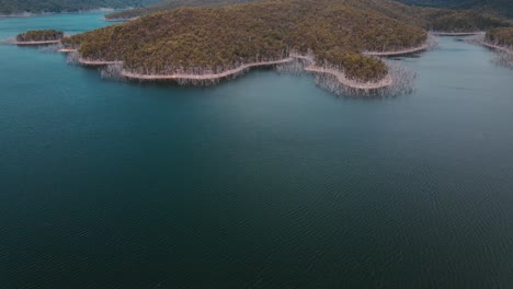 aguas tranquilas del lago advancetown cerca de la presa hinze - montaña exuberante rodeada de árboles muertos - costa dorada, queensland, australia