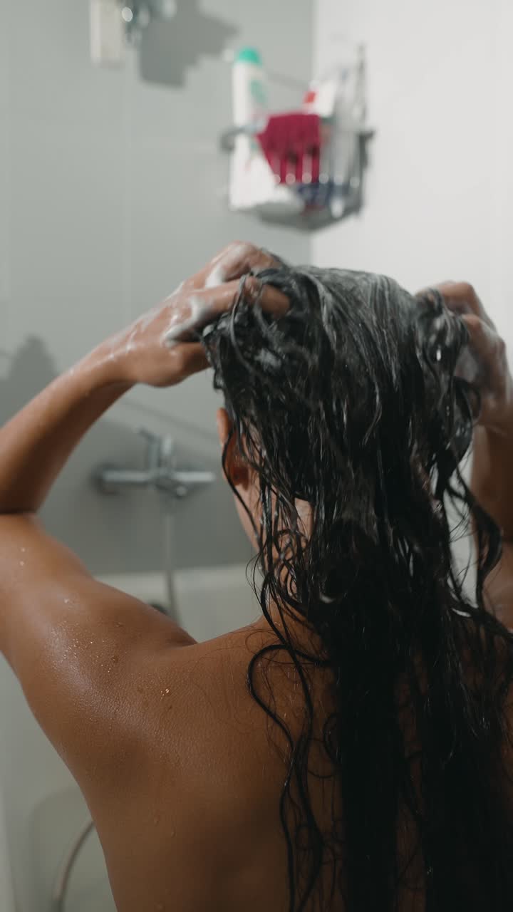 Donna che si lava i capelli sotto la doccia