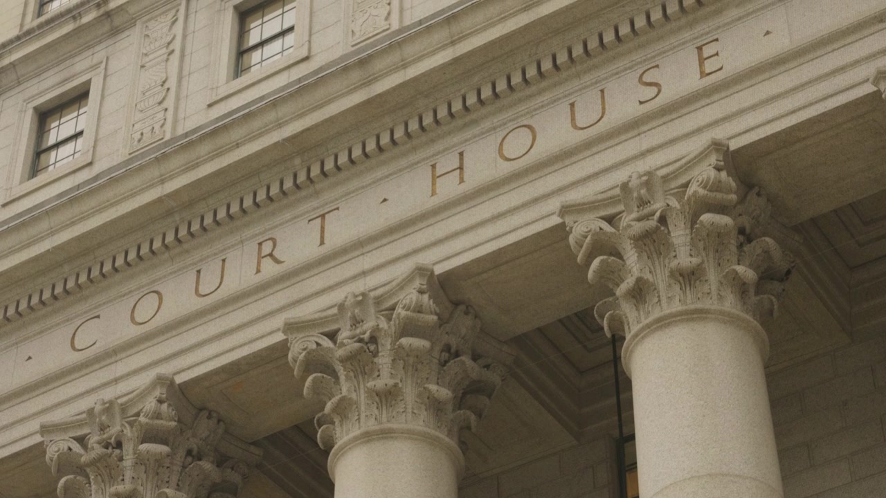 Ripresa inclinata al rallentatore della facciata di un tribunale degli Stati Uniti con la sola scritta "Court House" in una giornata nuvolosa