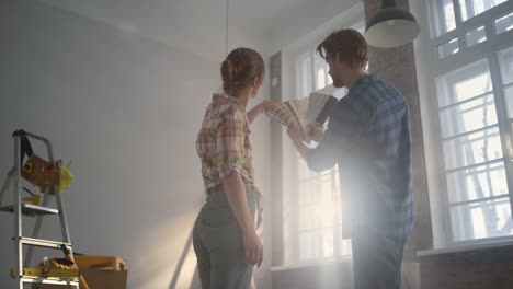 young family staying among construction tools. couple choosing walls color.