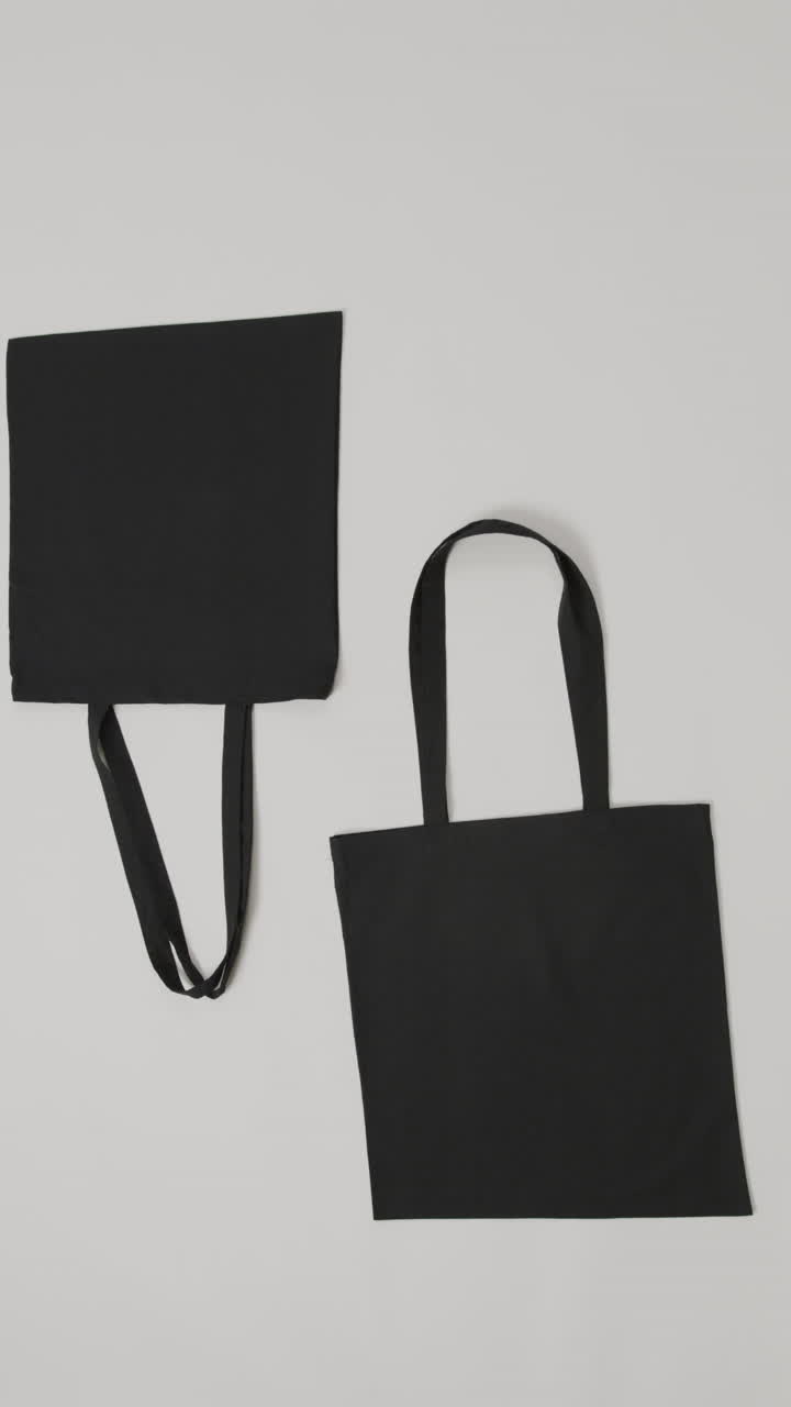Vertical video of black bags on grey background, copy space, slow motion