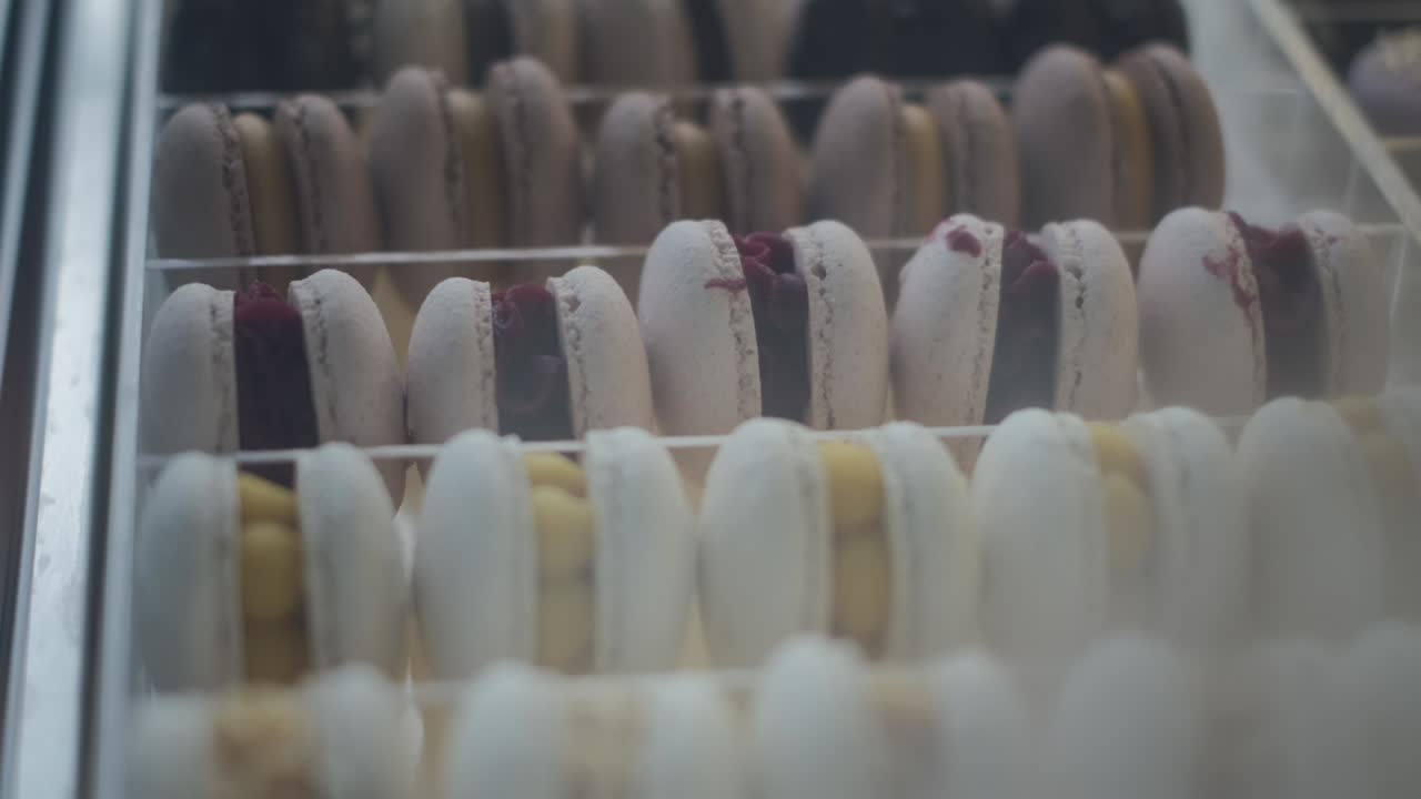 galletas apetitosas de diferentes colores y sabores en exhibición en una pastelería. pequeño negocio en la preparación de dulces y pasteles con chocolate y relleno de bayas en esmaltes