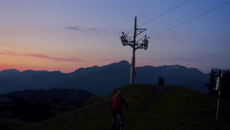 ciclista de montaña pedalea cuesta arriba en la oscuridad mientras se pone el sol
