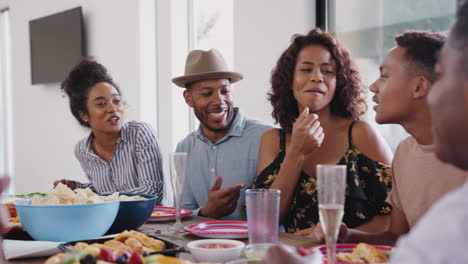 three generation black family sitting together at dinner table talking during a family celebration