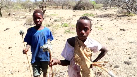 african children hunting birds in arid landscape