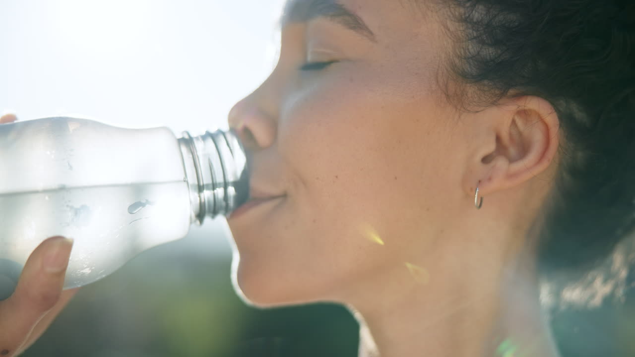 Donna felice, viso e che beve acqua nella natura.