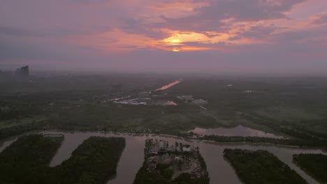 Vivid-sunset-hues-cast-over-the-flowing-water-channel-in-Hanoi,-Vietnam,-evoking-a-tranquil-yet-vibrant-urban-waterfront-scene