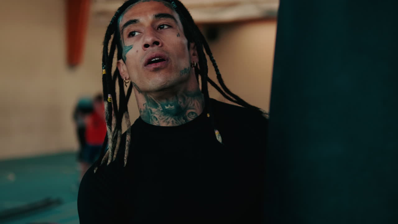 Uomo concentrato con dreadlocks e tatuaggi in palestra