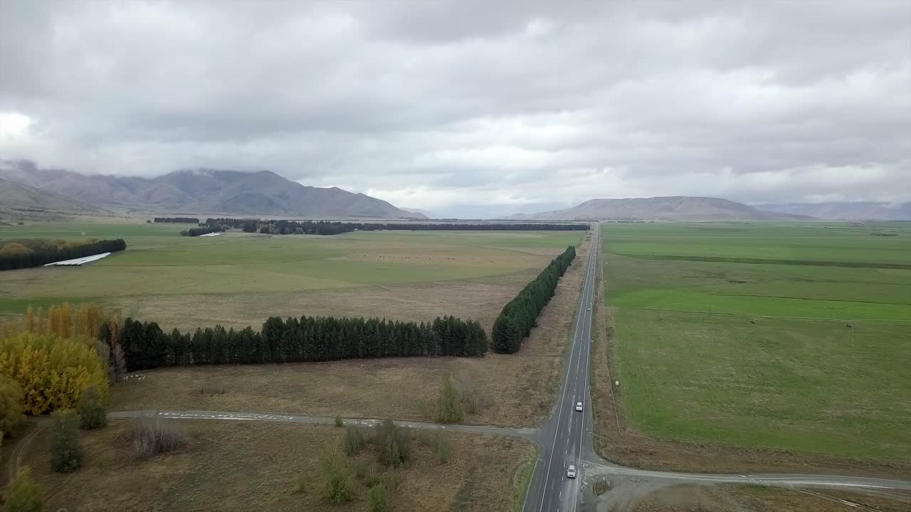 Aerial view of road through fields with mountains in the background