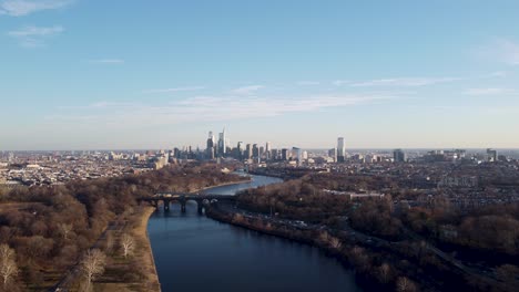 a beautiful aerial drone shot, drone flying over a river moving towards the philadelphia skyscraper skyline, pennsylvania
