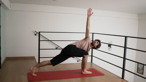 mestre de ioga a treinar num tapete vermelho num apartamento moderno.