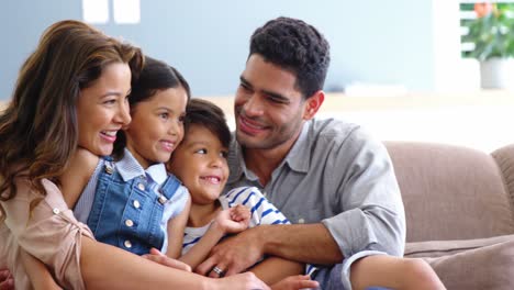 Glückliche-Familie-Sitzt-Auf-Dem-Sofa-Und-Umarmt-Sich-Im-Wohnzimmer