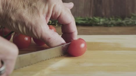 senior housewife cut cherry tomato in a wooden board kitchen table with sharp knife