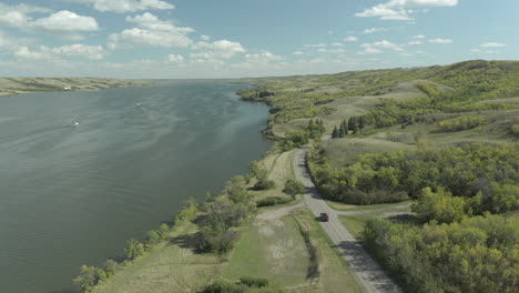 Truck-drives-past-lake-in-Buffalo-Pound-Provincial-Park,-Canada