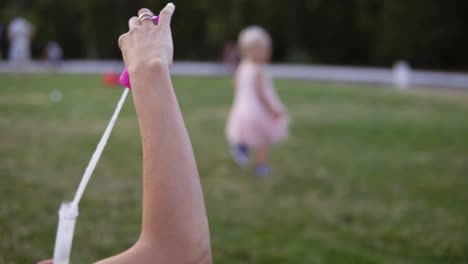 Footage-From-The-Shoulder-Mother-And-Her-Little-Daughter-Playing-Together,-Blowing-And-Baby-Catching-Soap-Bubbles