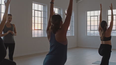 yoga class instructor teaching healthy pregnant women practicing warrior pose enjoying group training exercise in fitness studio at sunrise