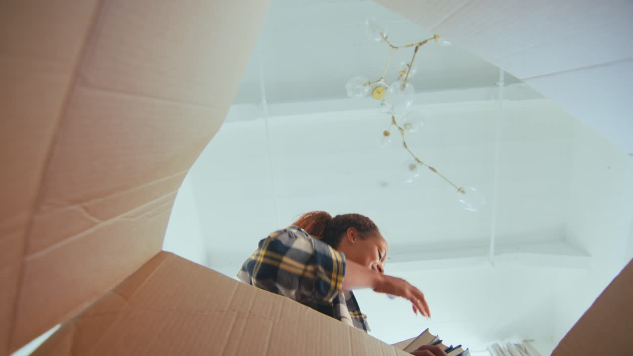 joven feliz casual mujer afroamericana estudiante pone libros en caja de cartón