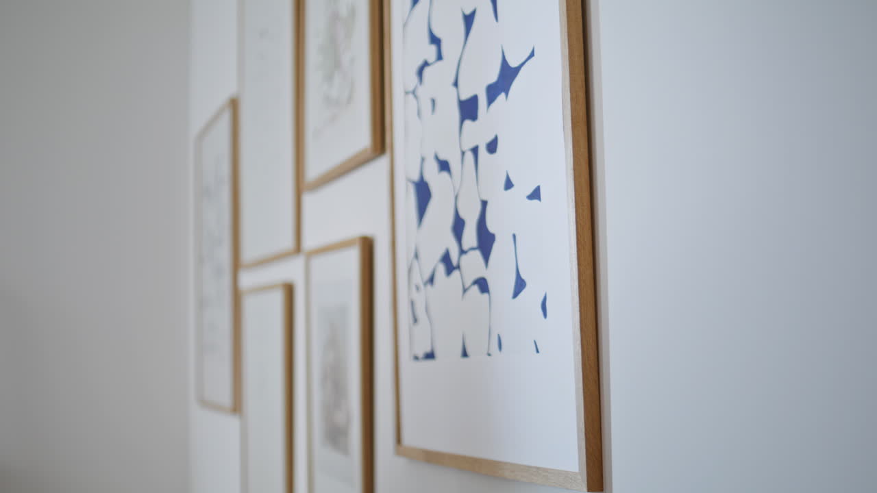 Hands correcting frame paintings on white wall modern apartment closeup