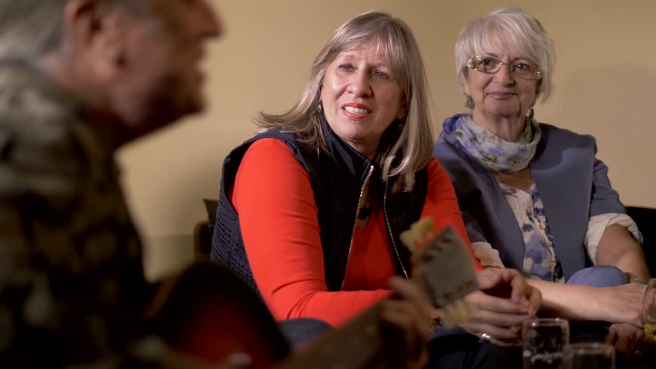 hombre de mediana edad tocando la guitarra en una fiesta en casa