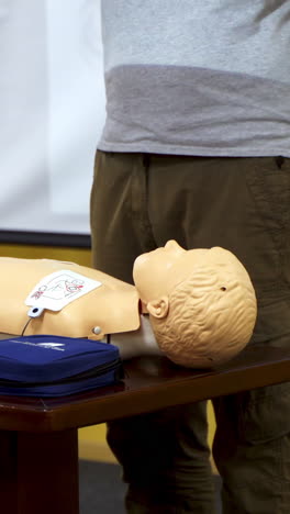 training for safe life of child. demonstrating chest compression on cardiopulmonary resuscitation baby doll. vertical video