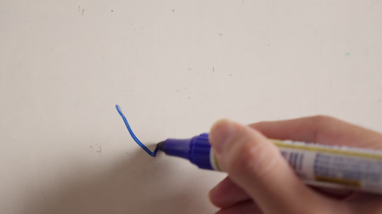 A hand drawing a blue checkmark on a whiteboard with a marker, close-up shot