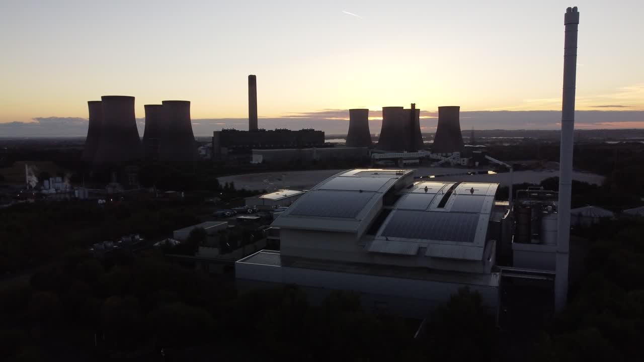 vista aérea del amanecer a través de la moderna fábrica solar en la azotea del reino unido y el horizonte de la estación de energía de combustibles fósiles