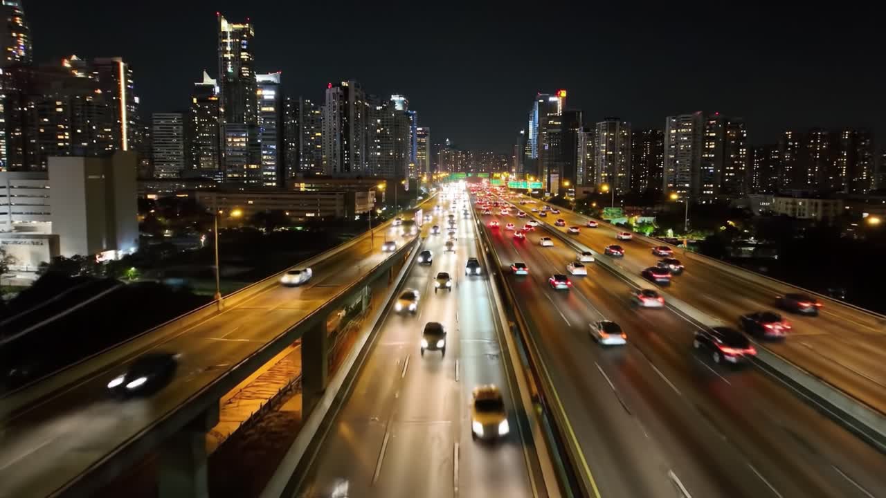 A vibrant night scene of a bustling urban highway filled with moving vehicles, showcasing the bright city skyline and illuminated buildings in the background