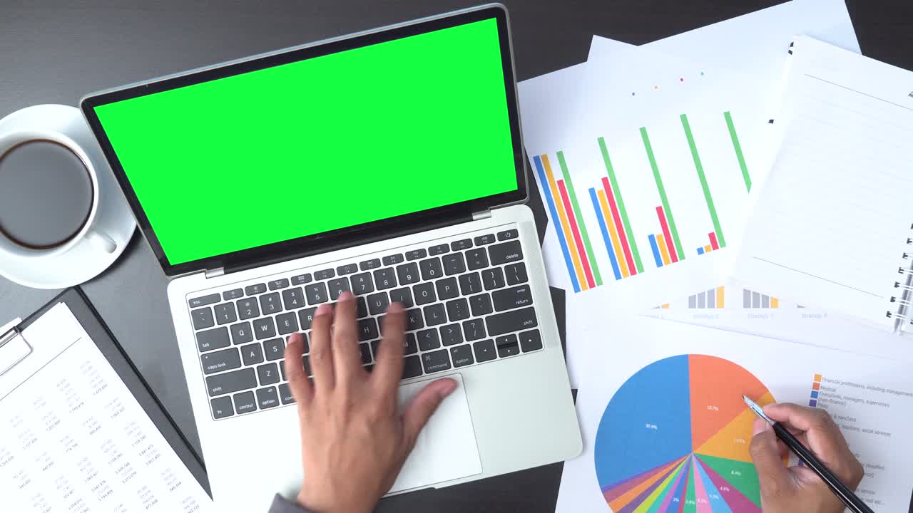 vista superior de un hombre de negocios trabajando con una computadora portátil de pantalla verde y documentos con gráficos y diagramas