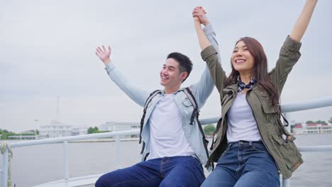 asian attractive romantic couple travel in the city for honeymoon trip. young new marriage man and woman backpacker tourist sitting on ferry hugging at each other spending time on vacation together.