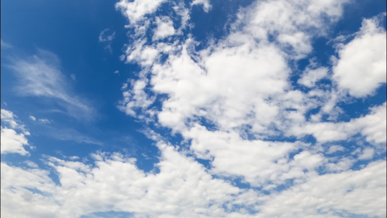 Azure blue sky is almost covered with thick cloudscape. Slowly, the cloudscape moves uncovering the sky. Low angle view. Timelapse.