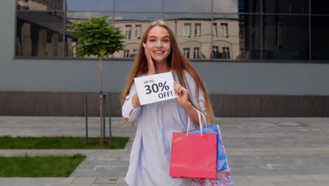 smiling girl showing up to 30 percent off inscriptions signs, rejoicing good discounts, low prices