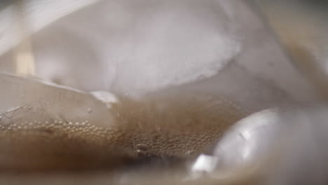 refreshing brown soda being poured over ice macro