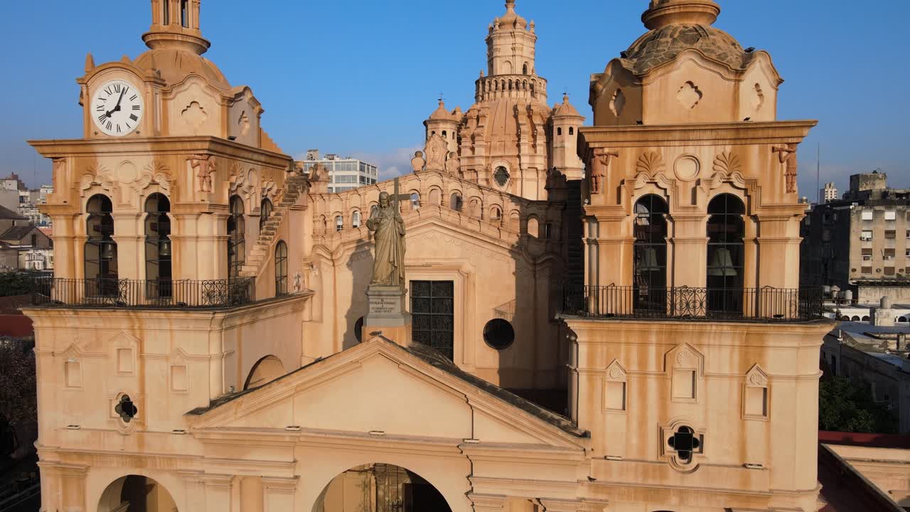 대성당 지붕에 있는 그리스도의 동상이 내려다보이는 공중 클로즈업 샷, 아르헨티나 코르도바에 있는 전체 교회 건물 외관을 보여줍니다.