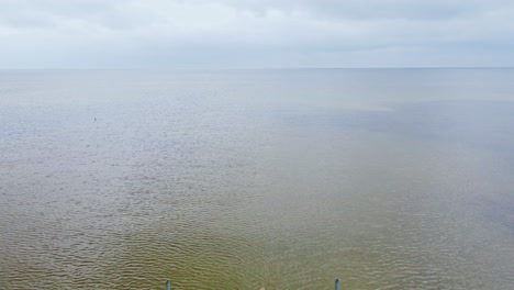 two cyclists pause at wooden pier's edge looking out over moody baltic sea