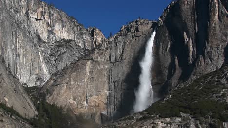 steep rocky mountains feature a spectacular waterfall and spray as it plummets to the bottom