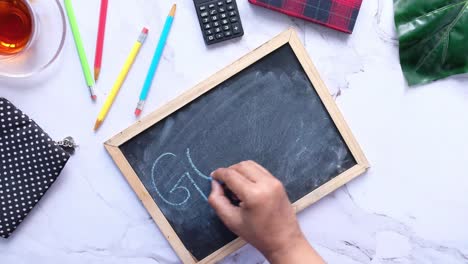 hand writing "goals" on a chalkboard with study supplies