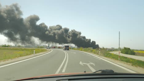 distant black smoke from wild fire, moving vehicle on main road, wide
