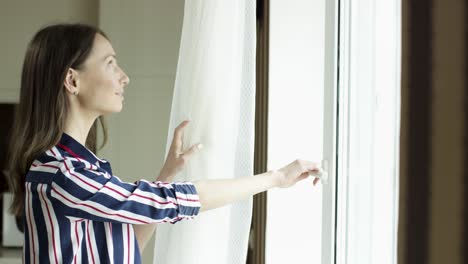 mujer mirando por una ventana de la cocina