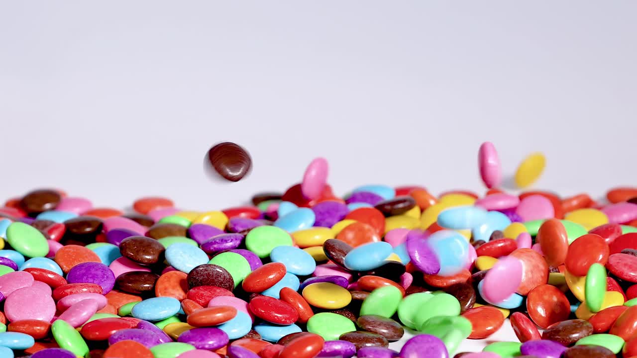 A vibrant assortment of colorful candies falling and gathering in a lively pile.