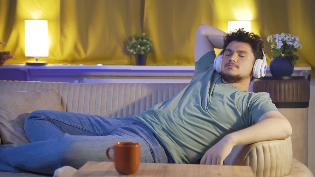 밤에 소파에서 음악을 듣는 남자. 즐겁고 행복합니다.