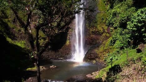 Drone-flying-through-tropical-vegetation-revealing-hidden-Viento-Fresco-Waterfall,-Tilaran-hike-trail