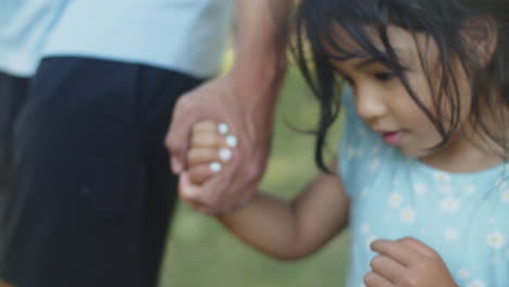 close-up of cute asian girl walking with father holding his hand