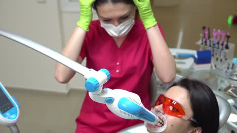 young woman getting uv whitening at the dentist's office by an ultra violet machine. shot in 4k