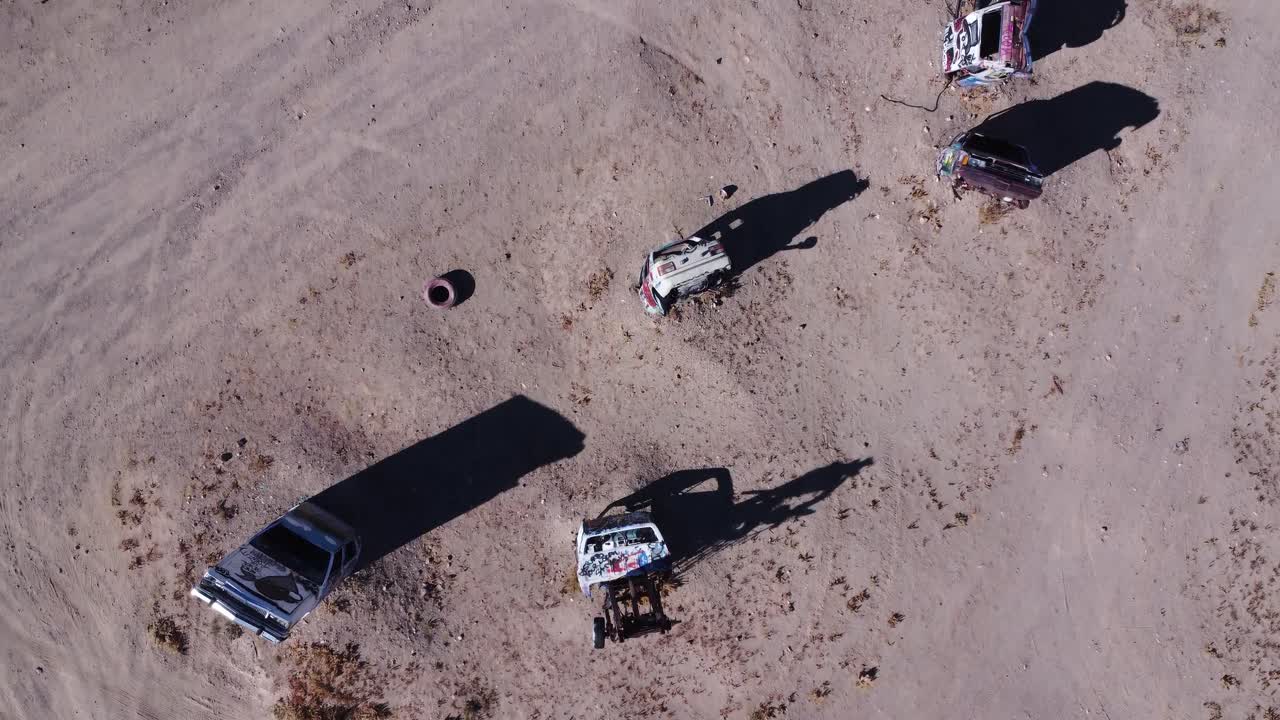 Birds eye view passover of a car graveyard ina desert